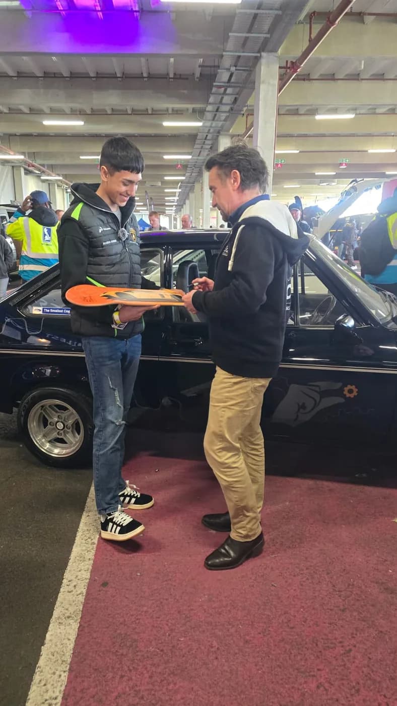 Oliver Rorzkowski at a car show, having a decorated board signed beside a classic car