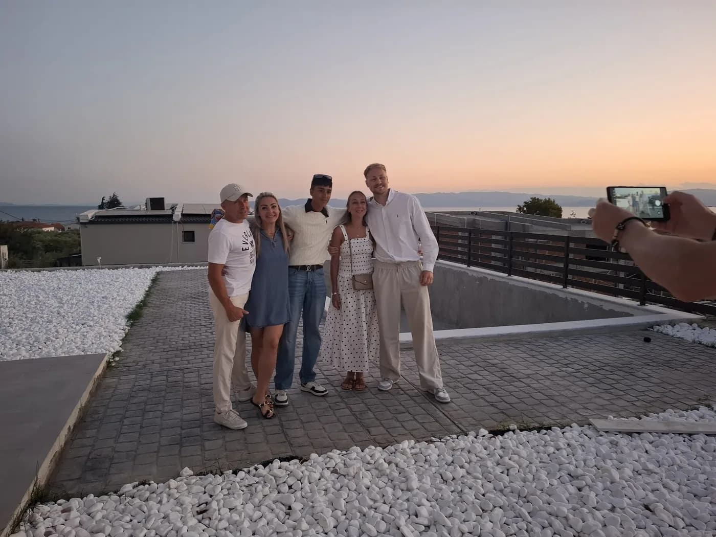 Oliver Rorzkowski with family on a rooftop terrace at sunset, the sea behind them