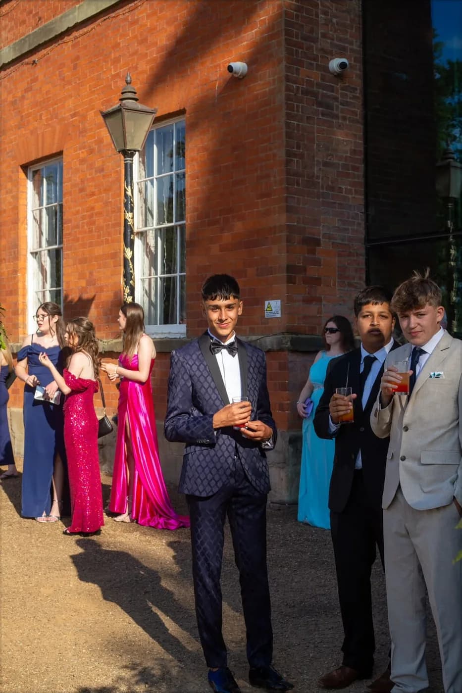 Oliver Rorzkowski in a navy patterned tuxedo and bow tie at a formal event outside a brick building