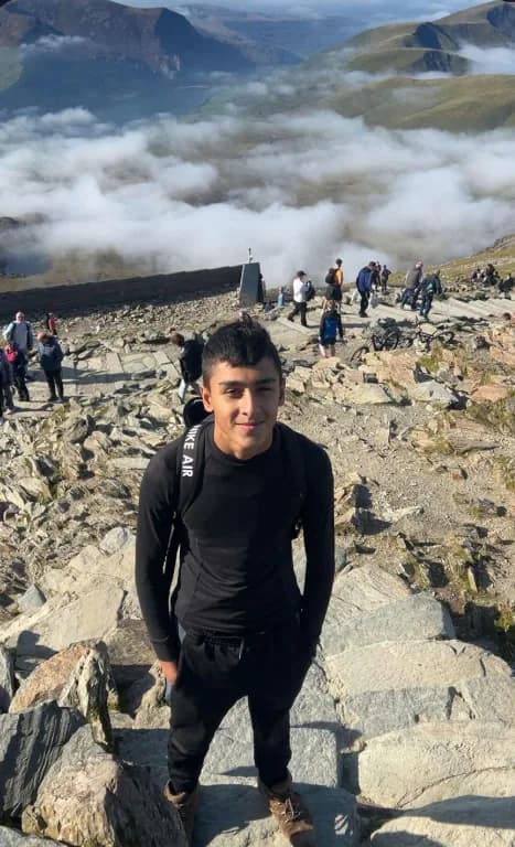 Oliver Rorzkowski hiking on a rocky mountain trail above the cloud line